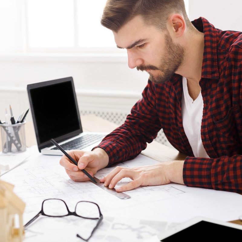 young-architect-working-with-blueprints-in-the-off-4S9JQT5.jpg
